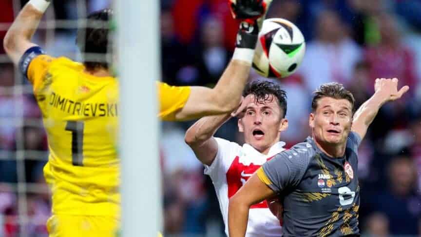 Gjanni Alioski pulling a silly face and jumping to challenge for a header while playing for North Macedonia