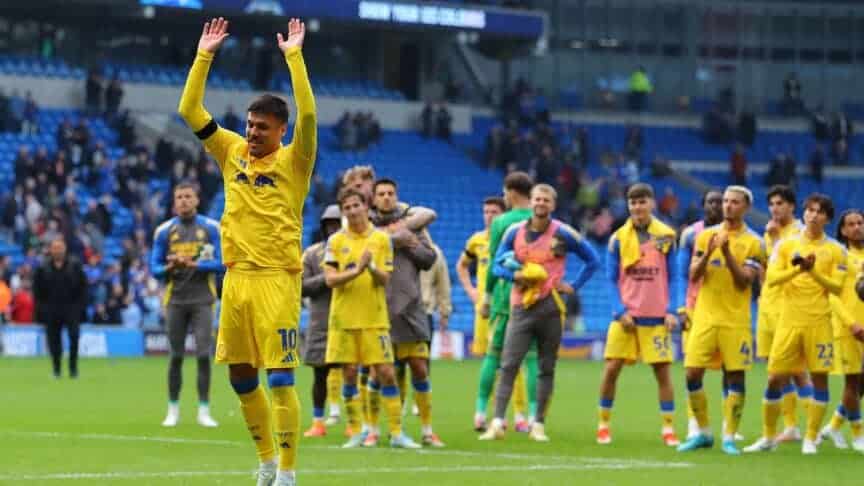 Joel Piroe waving his hands in the air to lead the cheers of the Leeds away end at Cardiff with the rest of the squad behind him, looking happier than many of the supporters felt