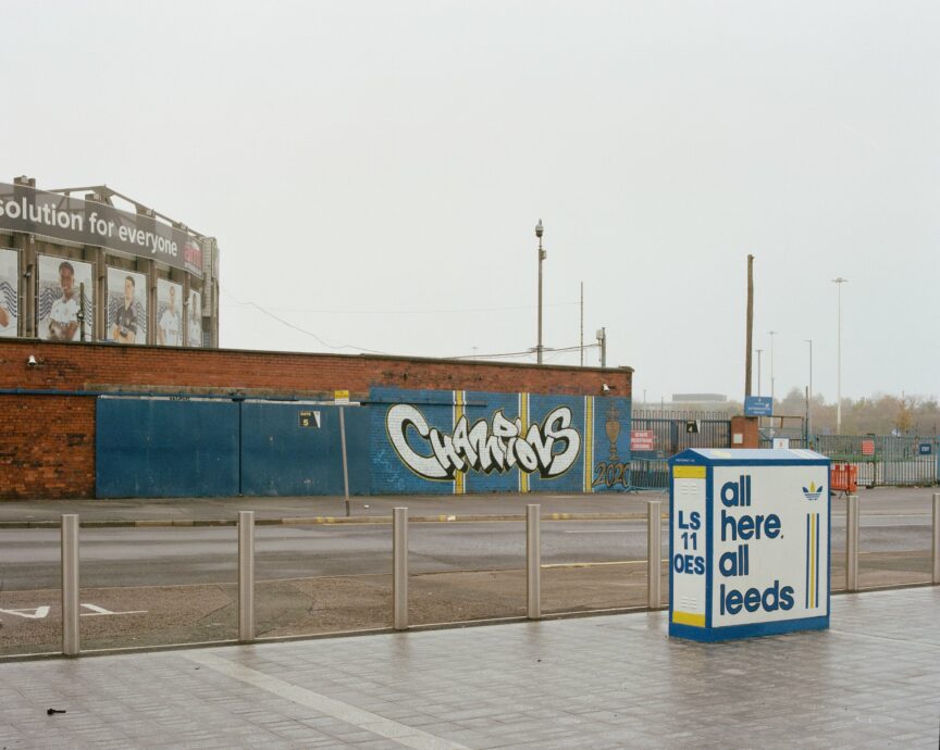 A photograph by Kate Schultze taken at Elland Road, with a bit of the north-east corner stand to the left, looking at Mateusz Klich's Champions mural and a junction box painted by Burley Banksy