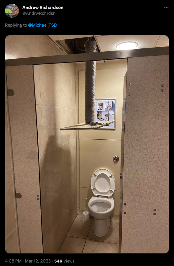A tweet of a photo of a toilet cubicle inside Elland Road. A ceiling tile has fallen down and is hovering over the toilet, attached to some piping