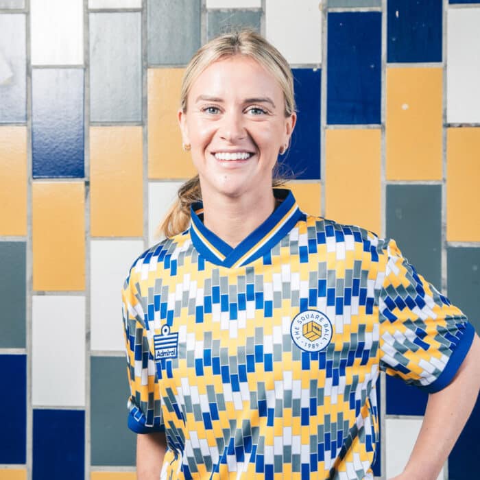 Olivia Smart of Leeds United Women wearing The Square Ball x Admiral 2023/24 Lowfields shirt, featuring a blue, yellow and white tiled pattern to replicate the walls of the Lowfields tunnel, in which she's standing