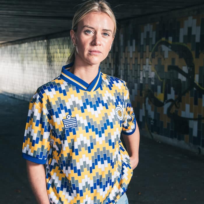Olivia Smart of Leeds United Women wearing The Square Ball x Admiral 2023/24 Lowfields shirt, featuring a blue, yellow and white tiled pattern to replicate the walls of the Lowfields tunnel, in which she's standing