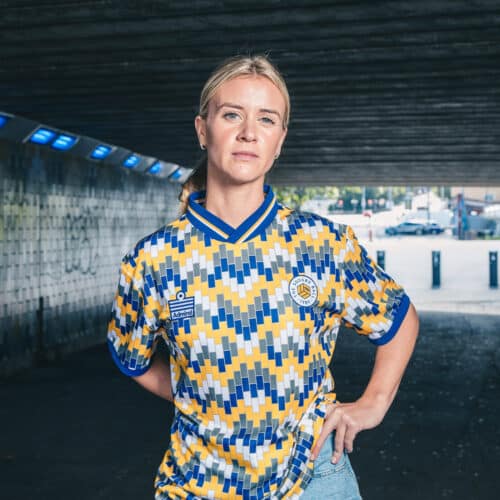 Olivia Smart of Leeds United Women wearing The Square Ball x Admiral 2023/24 Lowfields shirt, featuring a blue, yellow and white tiled pattern to replicate the walls of the Lowfields tunnel, in which she's standing