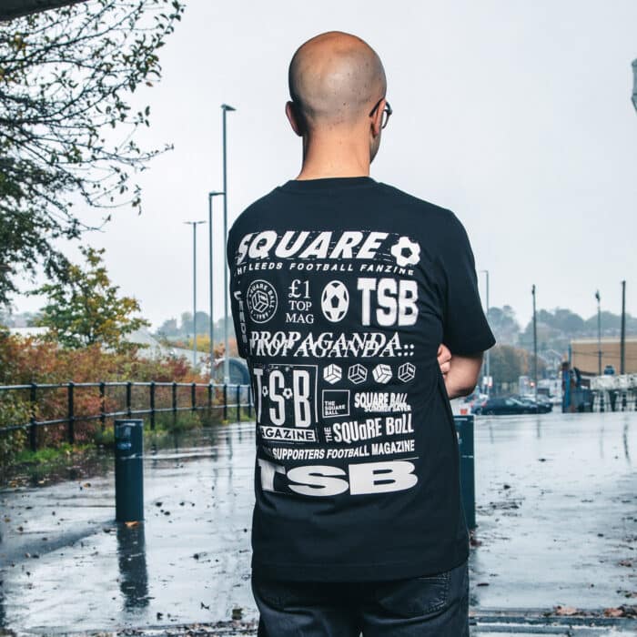 A photo of Michael wearing our retro logo t-shirt, showing a backprint featuring logos and graphics from throughout our history, and a front pocket print of the logo from the very first issue.
