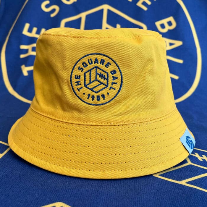 The yellow side of our reversible TSB bucket hat, with a blue embroidered 'The Square Ball 1989' crest