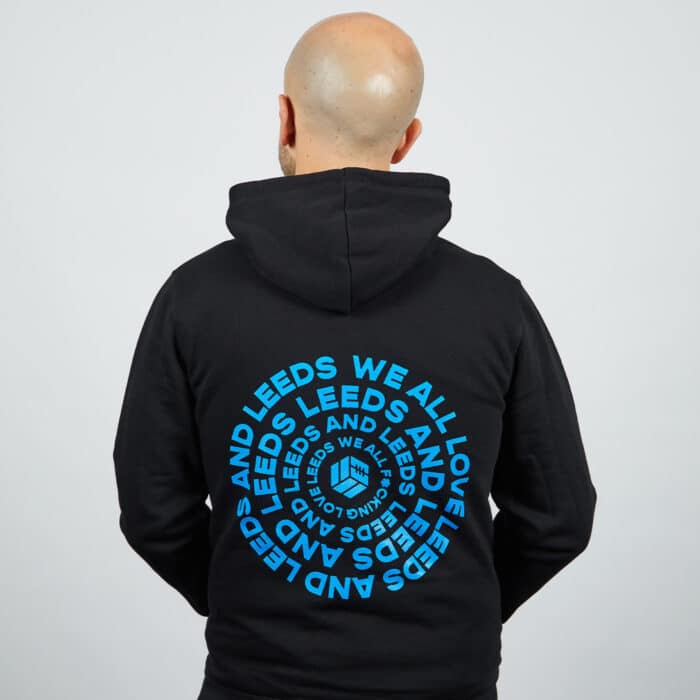 Our Michael wearing a black TSB WAFLL hoodie, showing off the spiralised blue backprint