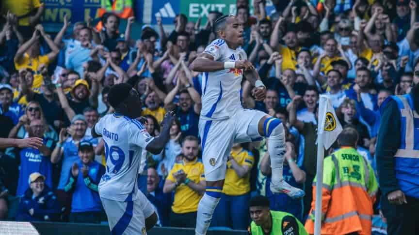 Mateo Joseph celebrating his opener against Hull, leaping into the air by the North-West corner, with Cody Drameh warming up in the background looking awkward