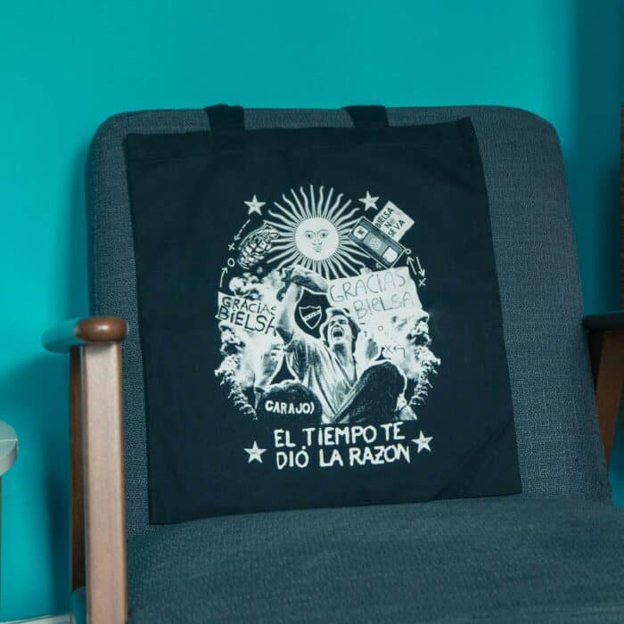 A black TSB Bielsa tote bag draped on the back of a chair — this is the 'El Tiempo' design