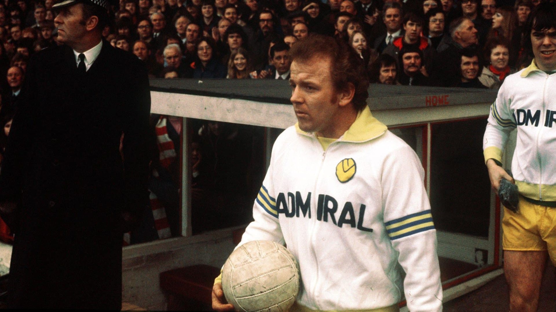 Billy Bremner walking out onto a pitch in 1973/74, his hair red and fuzzy, his Admiral tracksuit on point