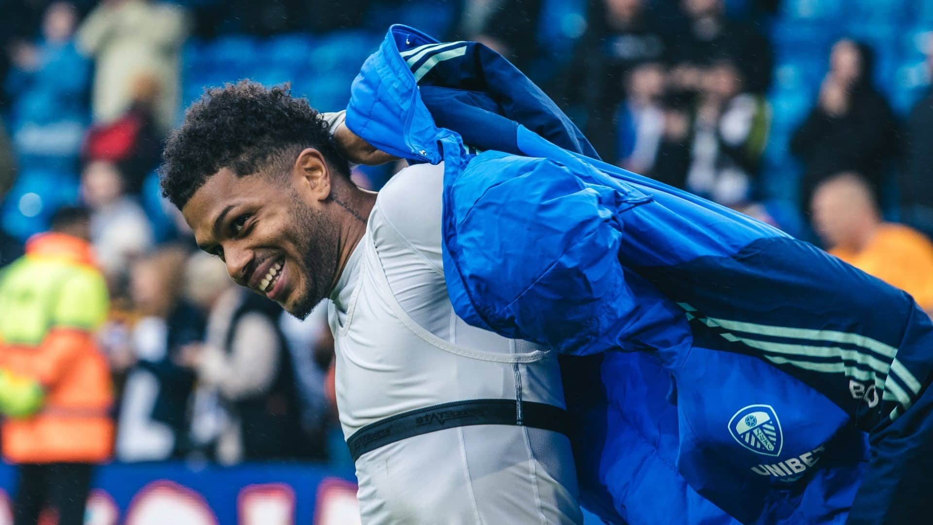 Georginio Rutter putting his big coat on at the end of Leeds' win over Huddersfield, grinning like he's the player of the match