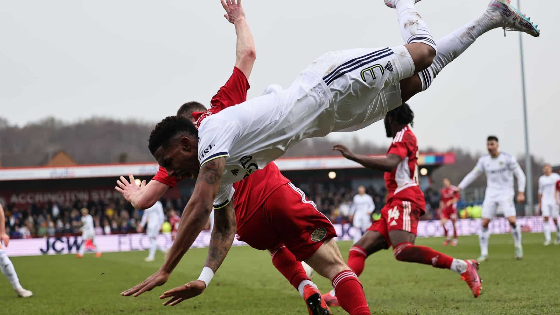 A close up photo from the sidelines of Junior Firpo, after being tackled, flying through the air at a daredevil angle