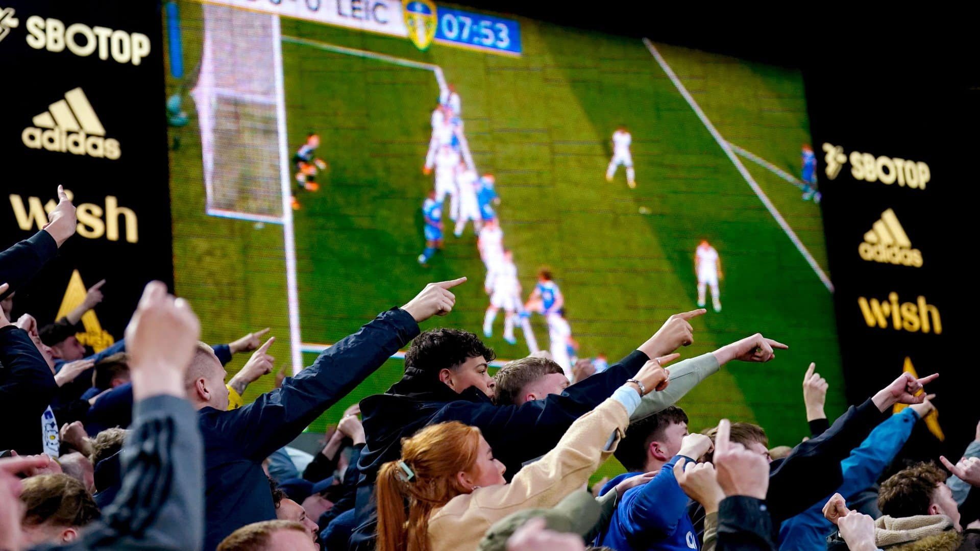 Fans in the South Stand communicating with their counterparts in the Leicester end regarding a replay of the Foxes' disallowed goal on the screen behind them and it's implications for their parenthood, morality, etc