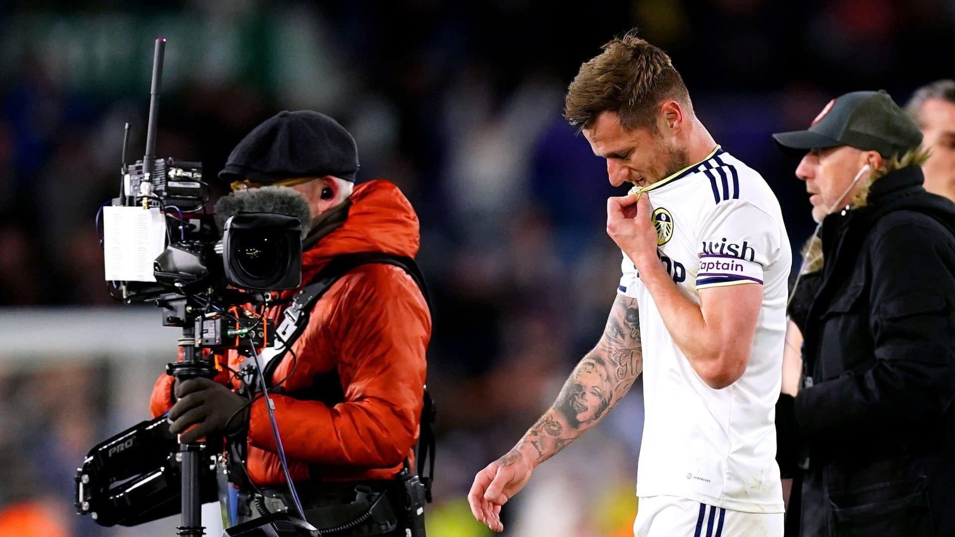 Liam Cooper walking off the pitch after defeat to Leicester, biting the collar of his shirt, while a TV camera points at his face