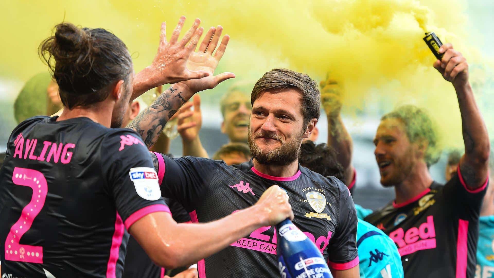 A photo of Luke Ayling high fiving Liam Cooper after Leeds had been crowned champions at Derby. Bill is holding a bottle of champagne, Barry Douglas is in the back ground holding a yellow flare