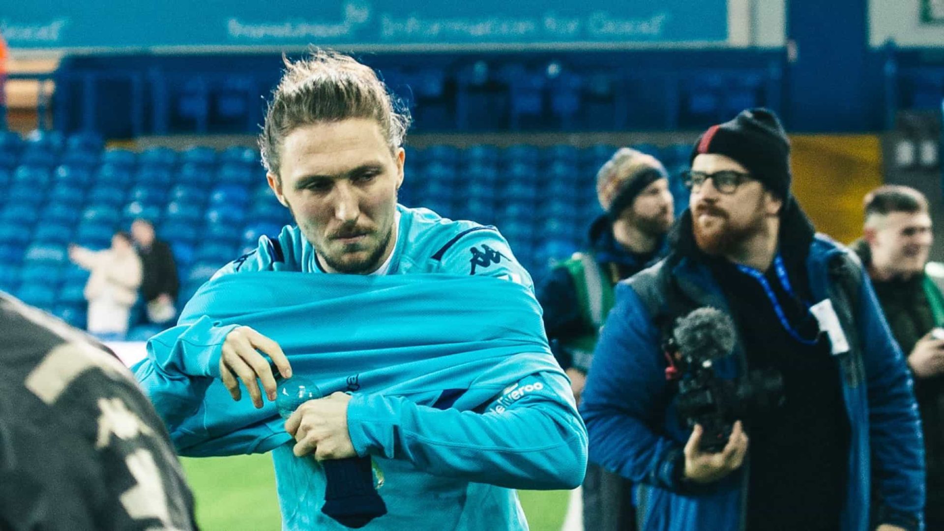 Luke Ayling putting a training top on and looking annoyed about things