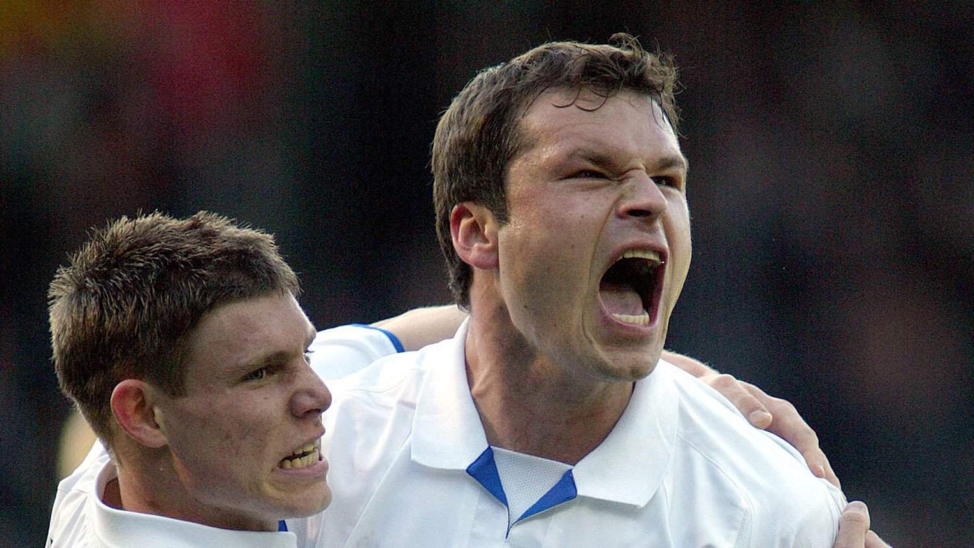 Mark Viduka is yelling a celebration, and a young James Milner is holding on to him for all he's worth