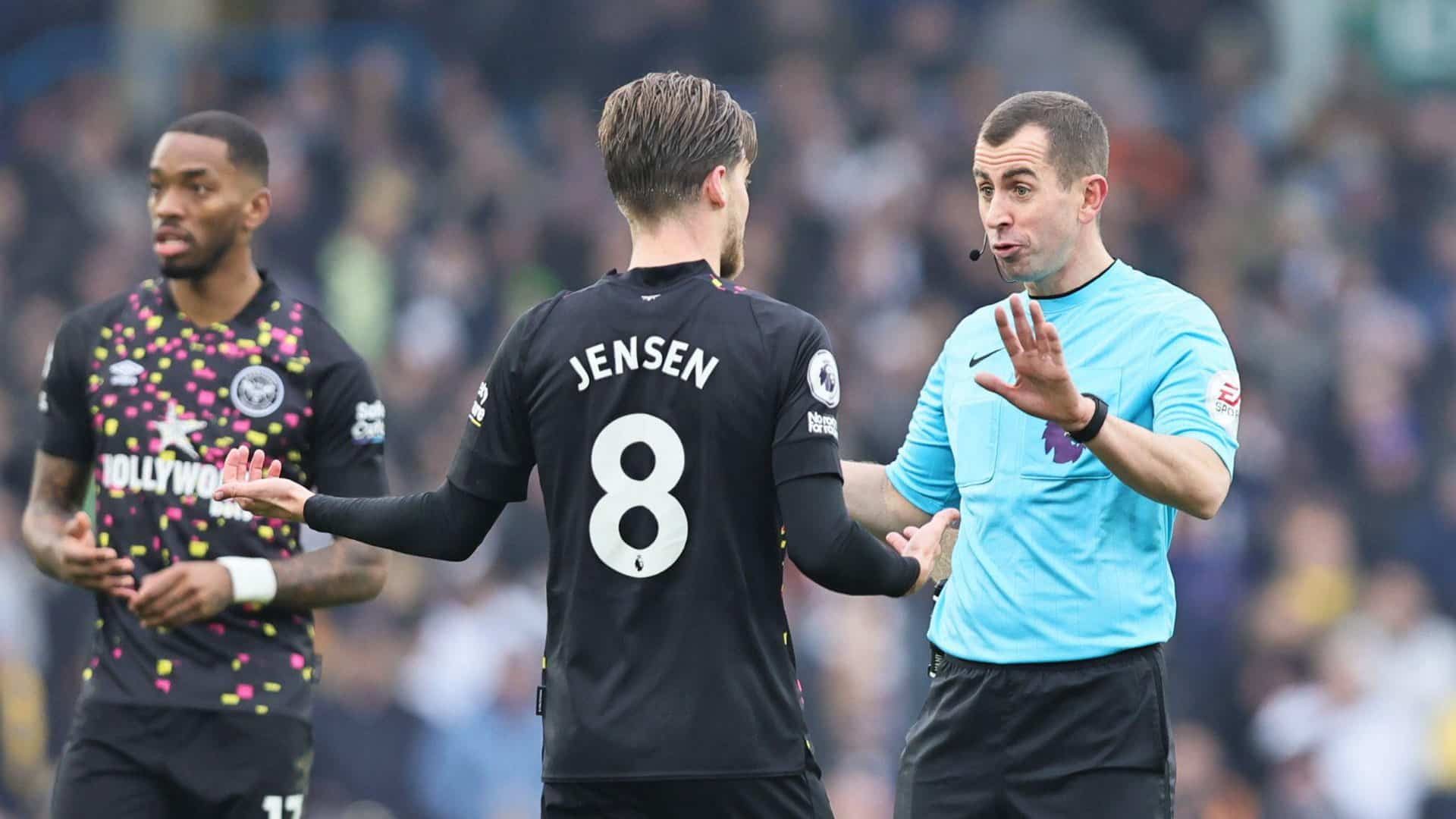 A photo of referee Peter Bankes discussion midfield strategy with Brentford's Mathias Jensen