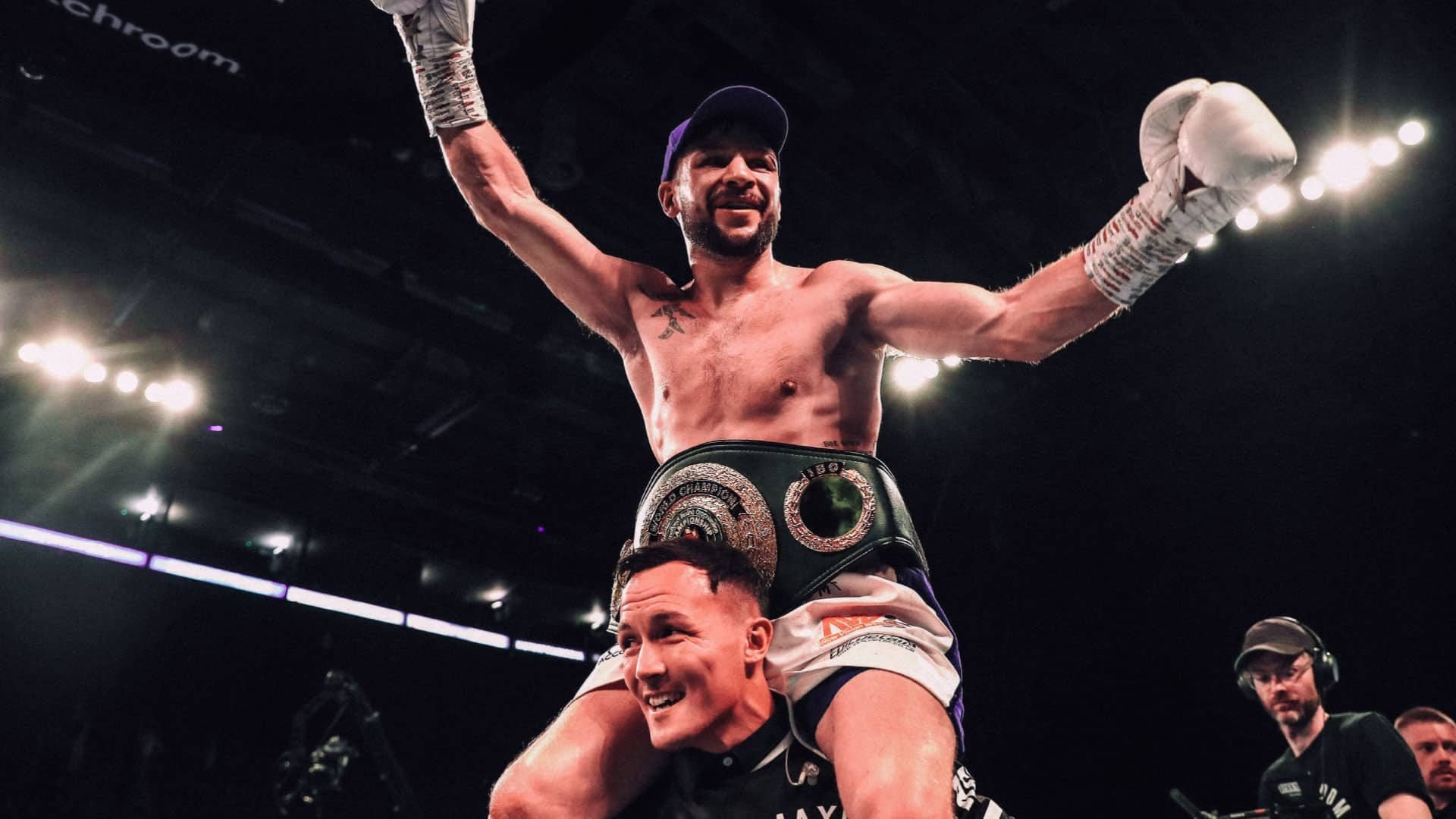 A photograph of Maxi Hughes celebrating a win, atop Josh Warrington's shoulders