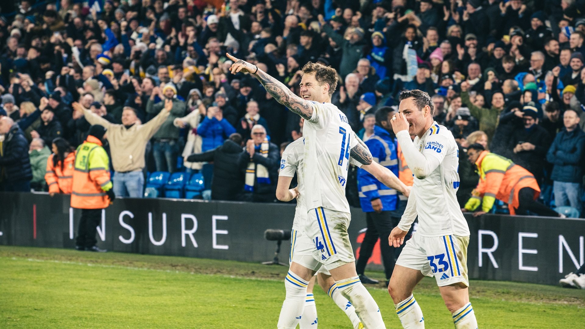 A photograph of Joe Rodon celebrating during Leeds' win over Leicester at Elland Road, winking at a teammate and pointing at them