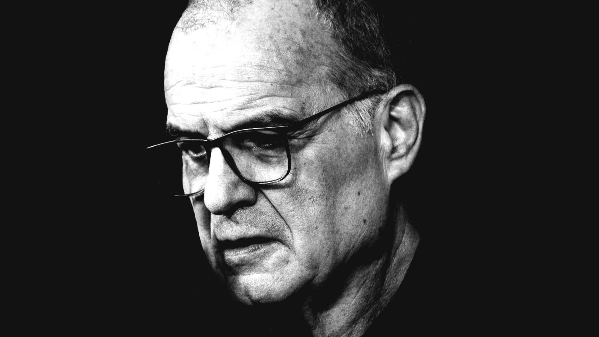 A black and white image of Marcelo Bielsa against a moody black backdrop