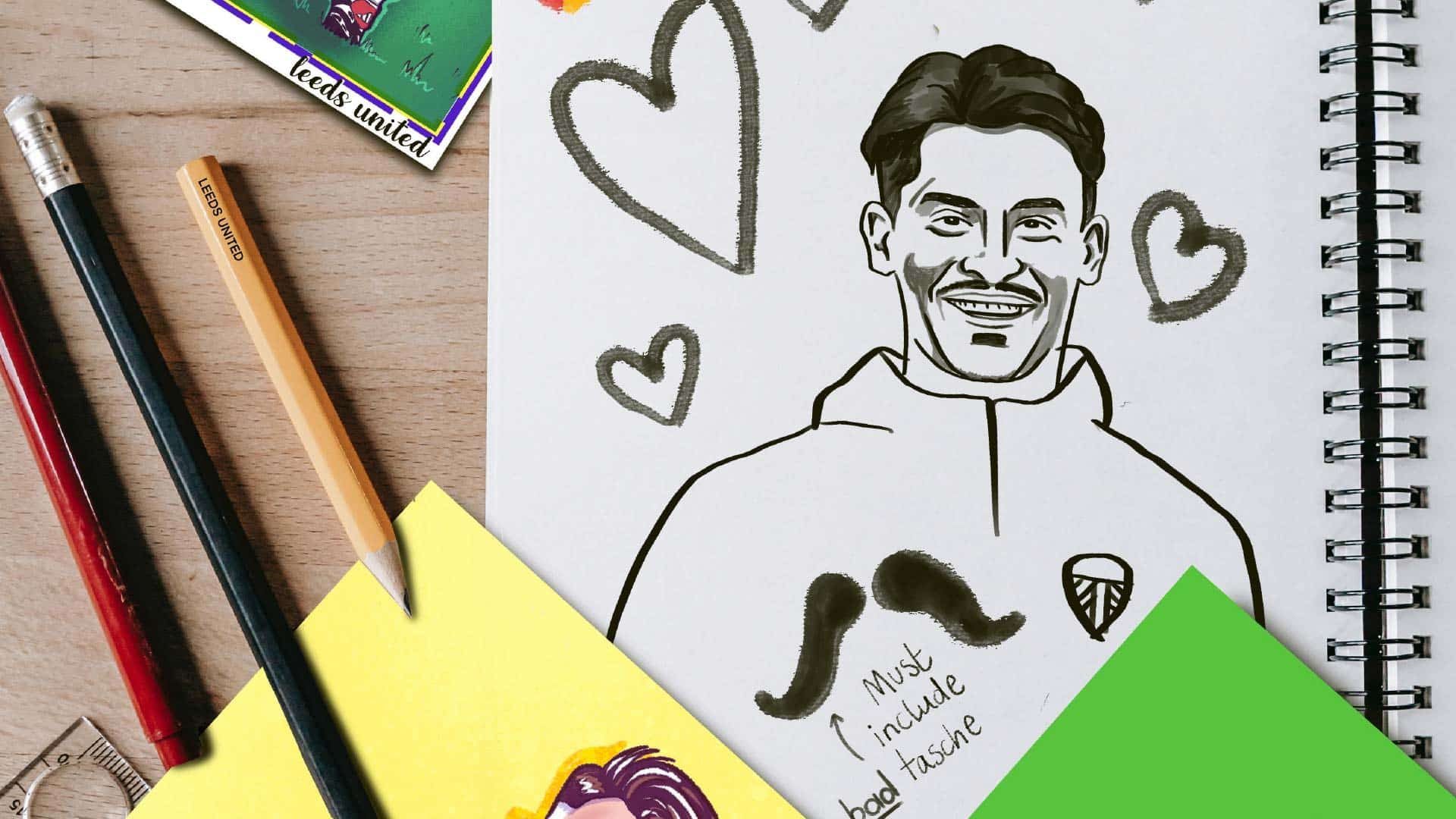 A notepad and some pencils, which have been used to draw a picture of Robin Koch surrounded by lovehearts and a nice big 'tash on the front of his jumper